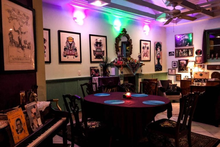 The main room is furnished with bohemian style decor and a piano.    