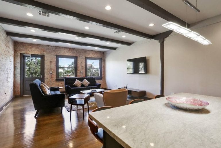 The open floor plan accents the exposed brick wall and bright windows of the private balcony. 