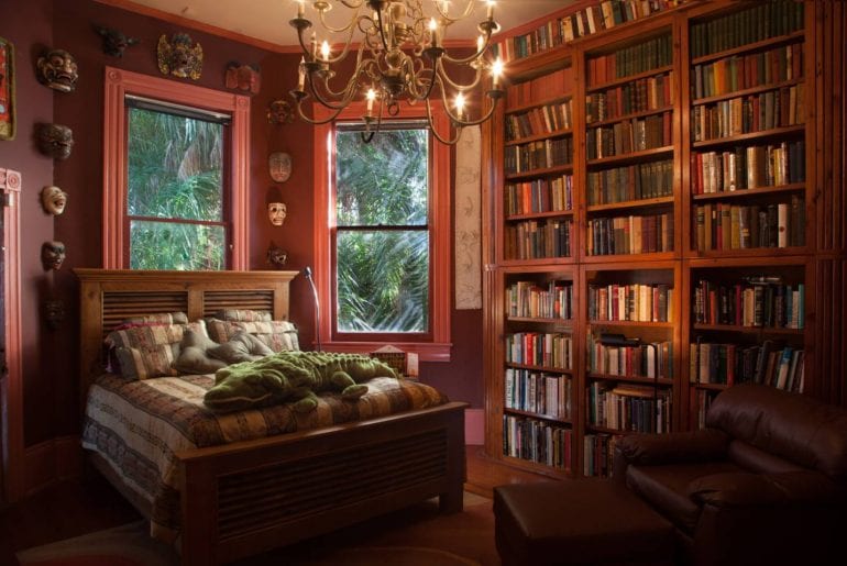 Floor to ceiling bookshelves fill this gorgeous bedroom along with unique artifacts and art