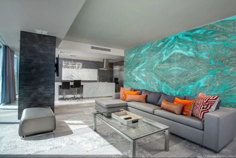 The living space has comfortable couches with orange cushions and a color changing LED wall