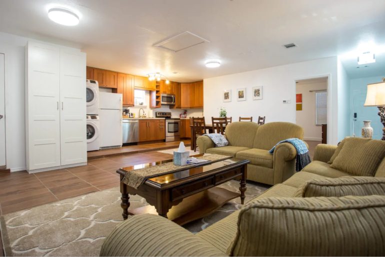 There is a spacious living area with a cozy sofa, gourmet kitchen, and a cute dining area