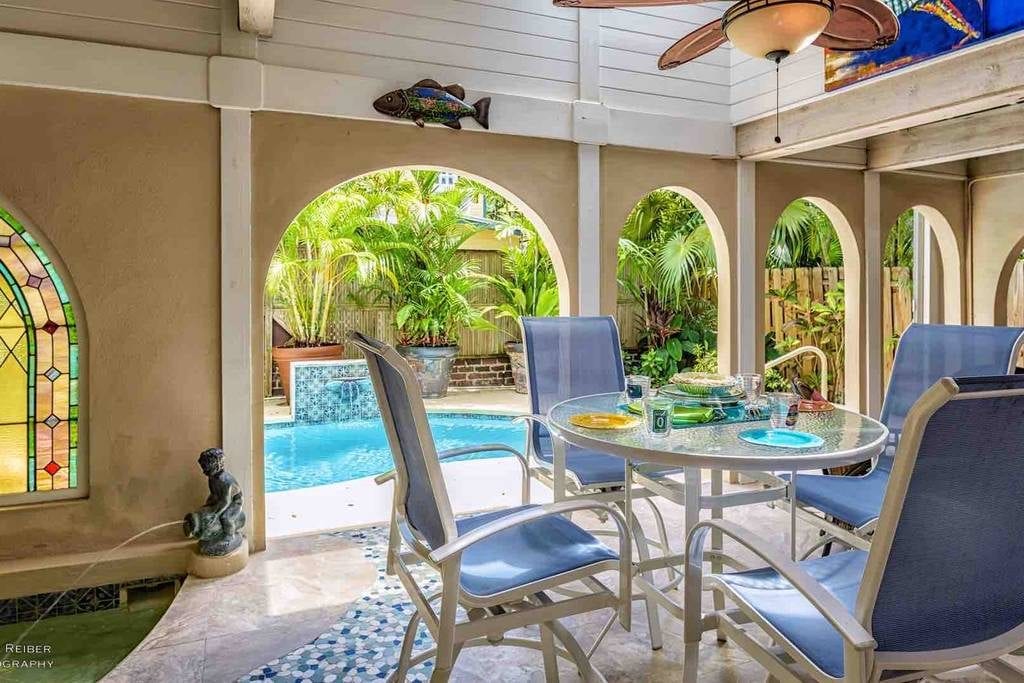 Key West property's pavilion featuring a grotto spa, patio furniture, and view of the in-ground pool with waterfall