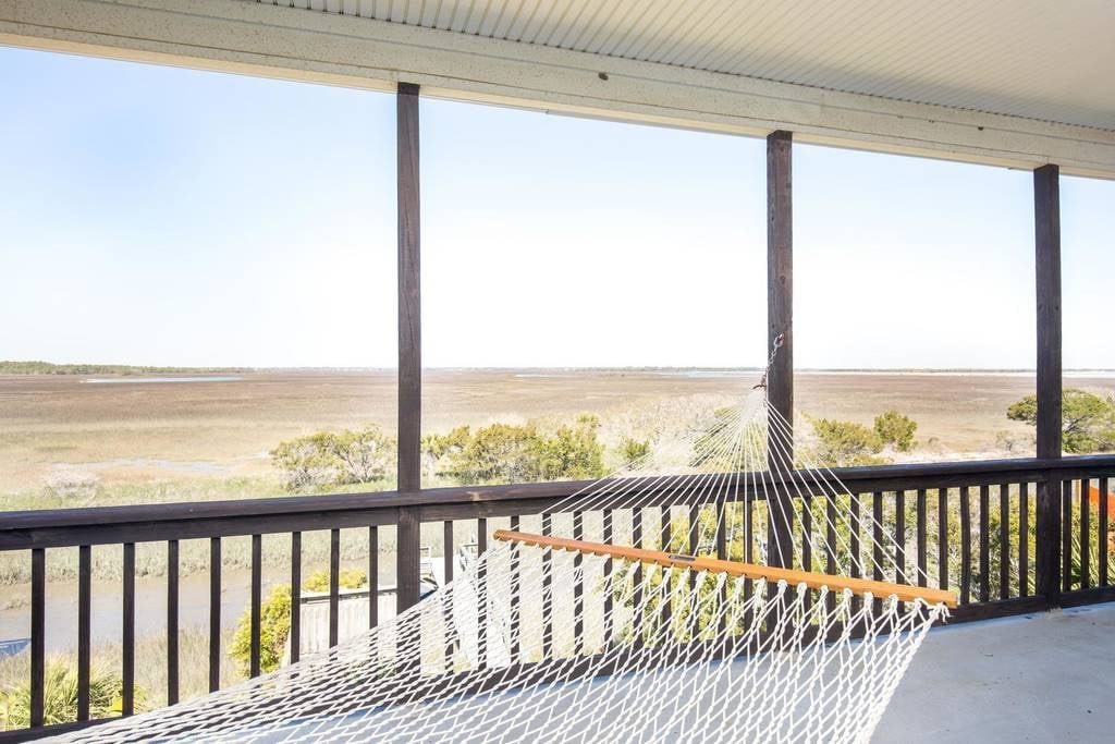 Hammock swings in this screened-in porch overlooking the marsh at Charleston Airbnbs near beaches