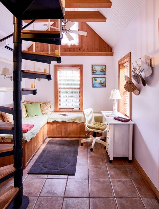 Folly Beach tiny home features a desk, wrap-around bench, and a spiral staircase