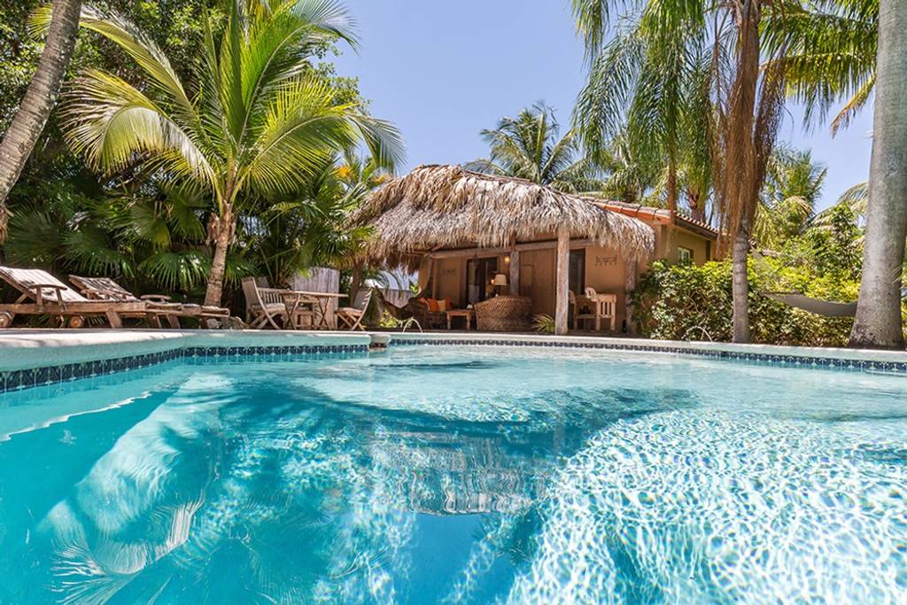 A swimming pool in front of a straw hut and some palm trees in West Palm Beach