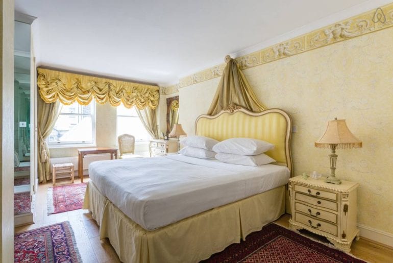 a bed with a gold headboard with some gold curtains behind it