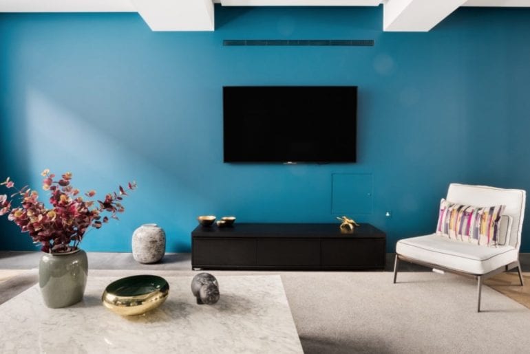 blue wall with mid century chair and elegant marble coffee table in the foreground