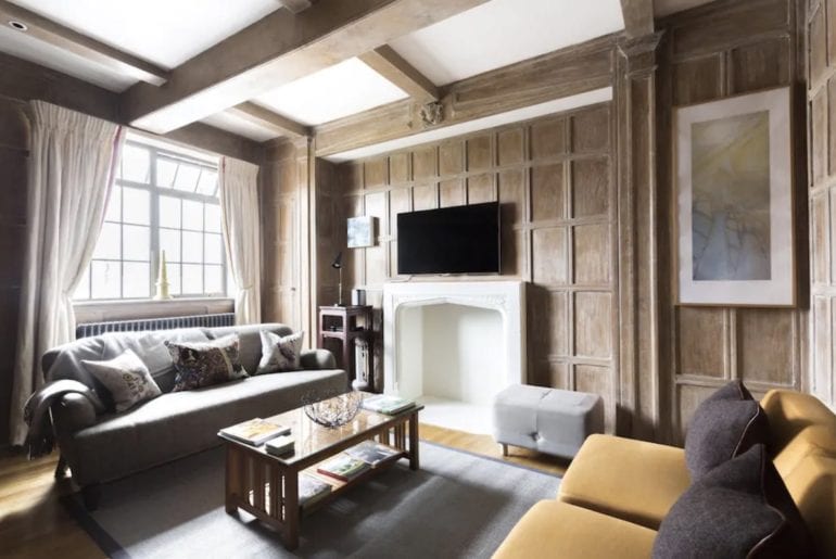 two sofas and a coffee table on a grey carpet in a wood panelled room