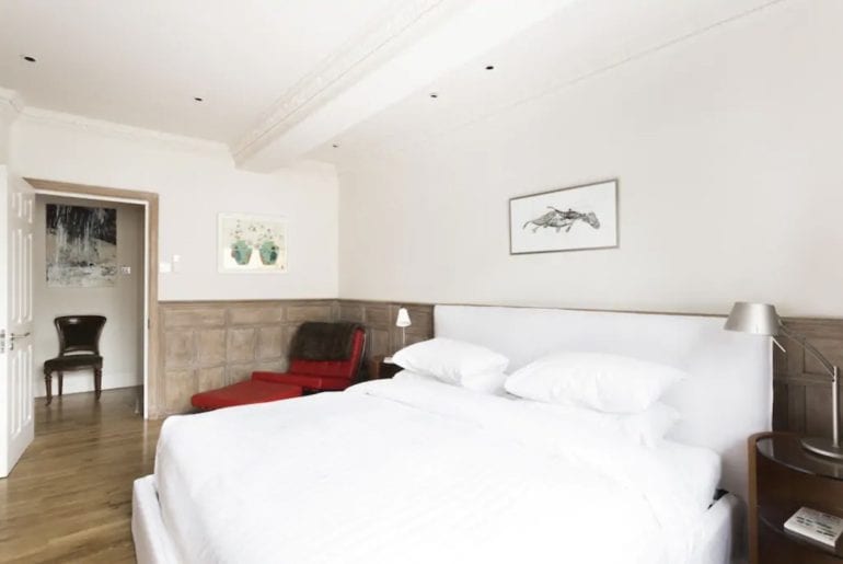 a double bed with white linen on it in a wood panelled bedroom 