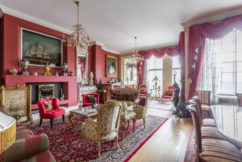 gold chairs on a red rug with a picture of a boat on the wall in an Airbnb in Kensington, London