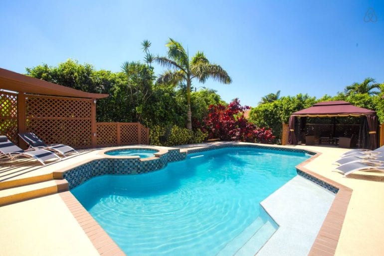 a pool with palm trees around it in the sunshine