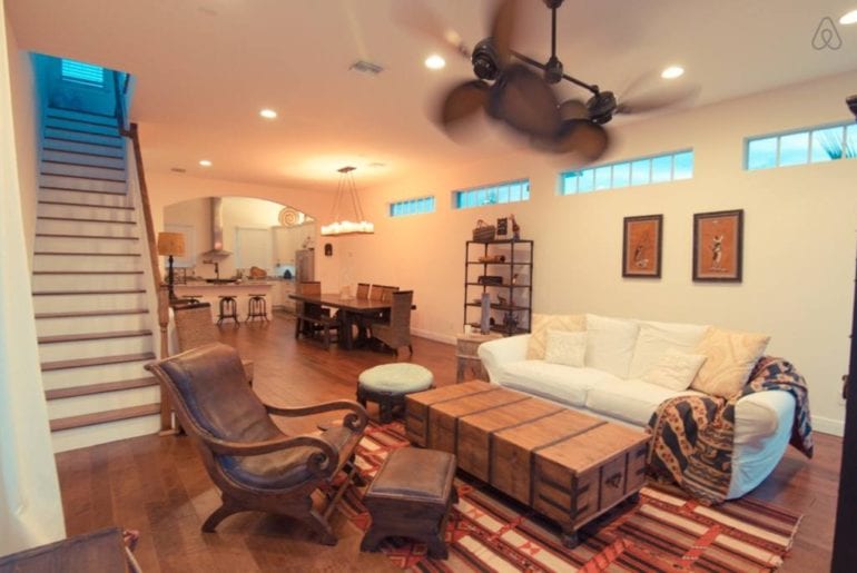 a sofa with a wooden chest in front of it and some stairs to the left in an Airbnb