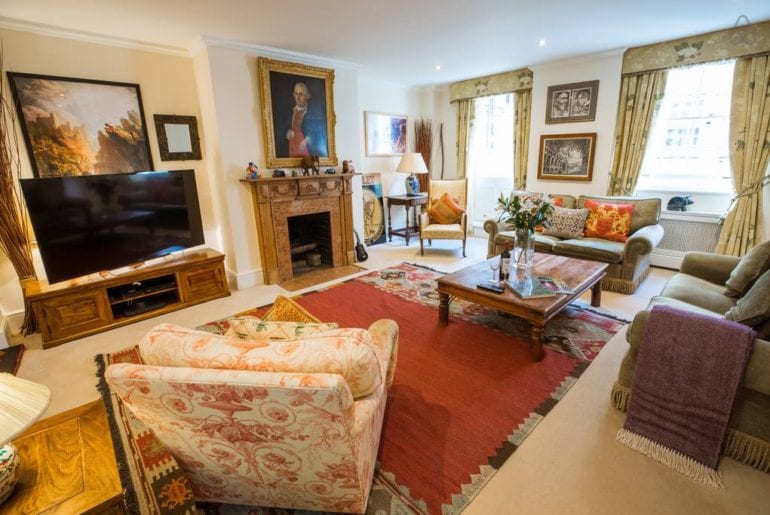 a living room with a portrait above the fireplace in a Chelsea Airbnb