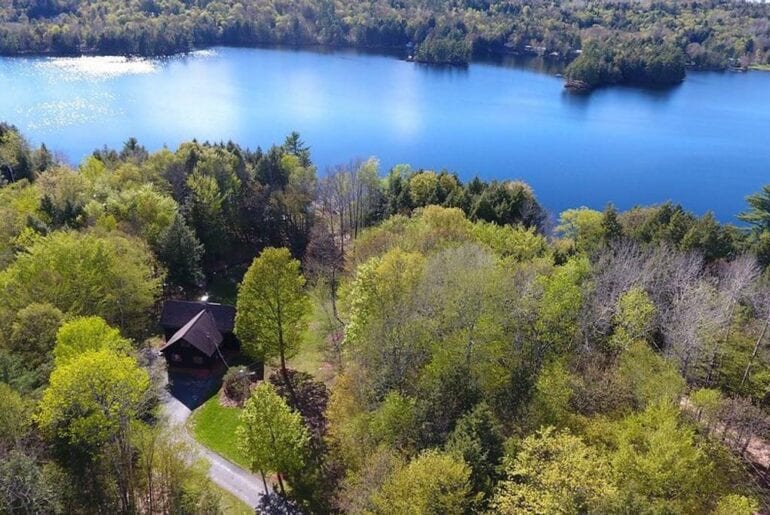 The home is surrounded by lush greenery and a calming lake